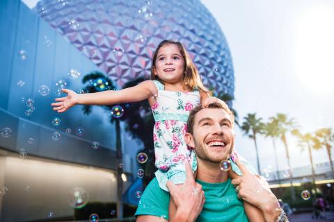 A father walks through Epcot with his daughter on his shoulders