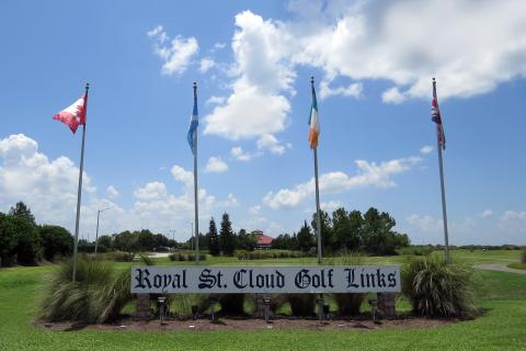 A sign that says Royal St. Cloud Golf Links with flags and a fairway in the background