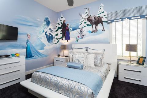 A Frozen-themed bedroom in a Kissimmee vacation home featuring character wall art of Elsa, Anna, Olaf, and Sven, with blue and white bedding and modern furnishings.