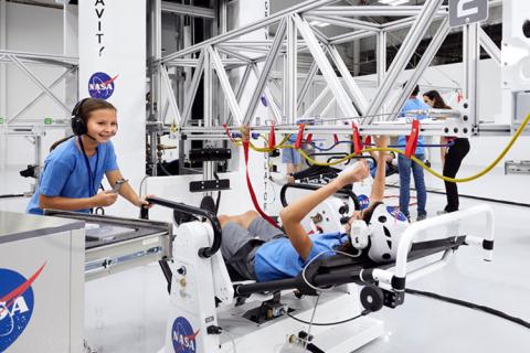 Children participate in a hands-on astronaut training simulation at the Kennedy Space Center Visitor Complex, wearing NASA gear and testing equipment designed to mimic space missions.