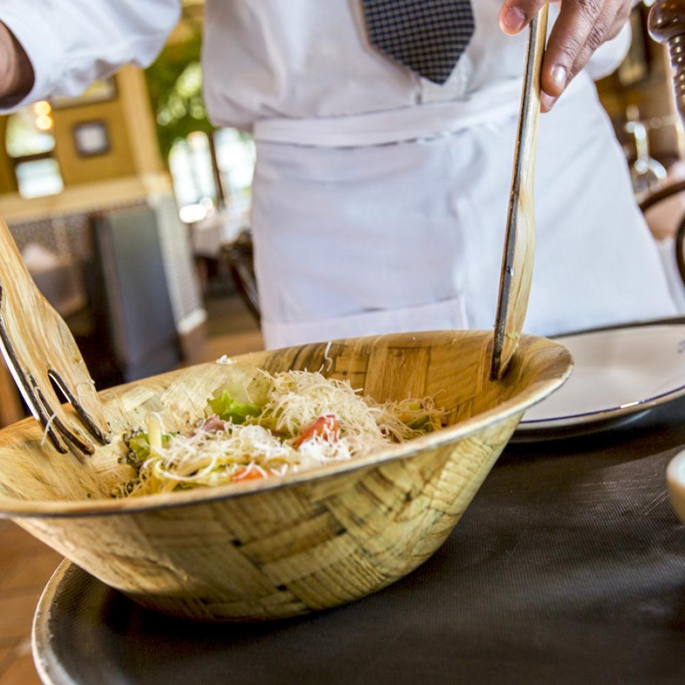 Close up of a chef tossing a salad in a wooden bowl with wooden utensils at Columbia Restaurant