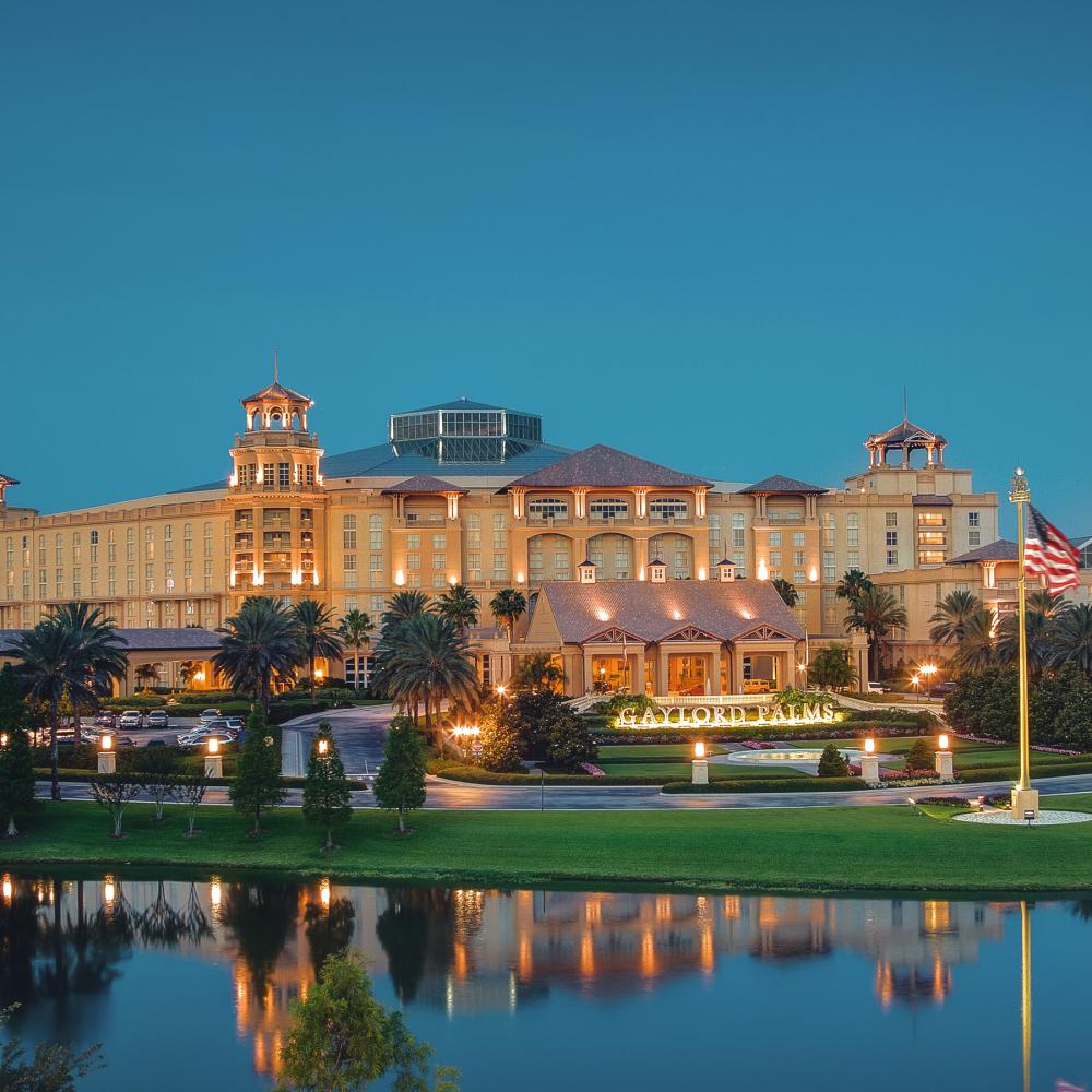 Beautiful exterior of Gaylord Palms Resort at dusk with clear reflection in the water below.