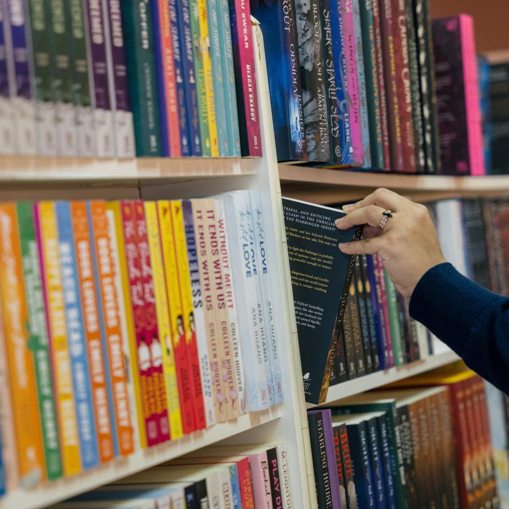 A person pulls a book out of a shelf.