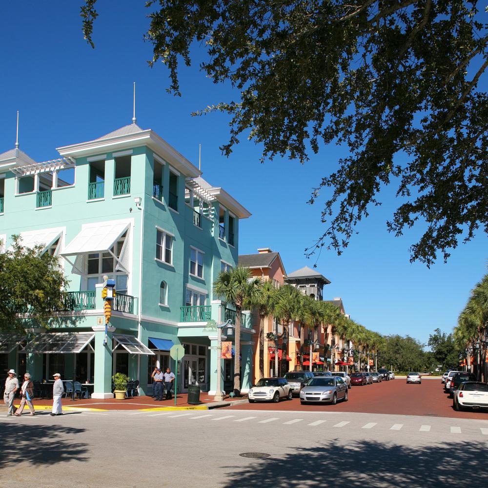 A sunny tree-lined street with colorful homes and businesses in Kissimmee, Florida.