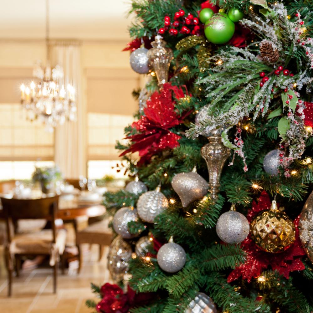 Beautifully decorated Christmas tree with red poinsettias, silver and gold ornaments, and twinkling lights inside a festive Kissimmee vacation home dining area.