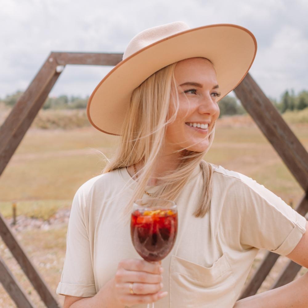 Angela Jones holding a glass and wearing a hat