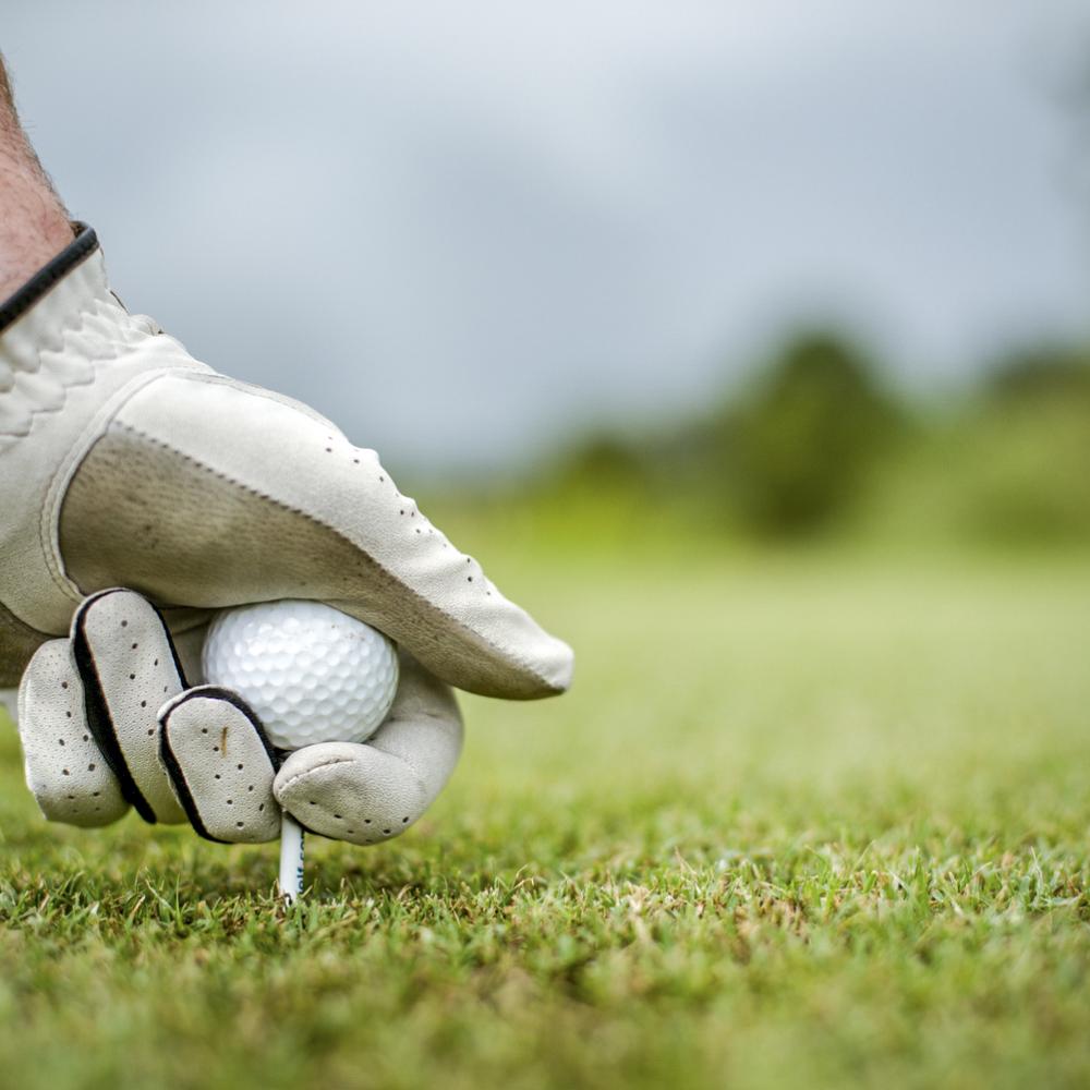A man sets a golf ball on the tee 