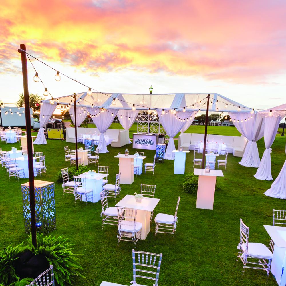 Tables chairs tents and lighting set up for an outdoor event during the Kissimmee sunset