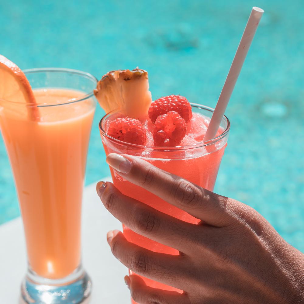 two fruity drinks being enjoyed poolside 