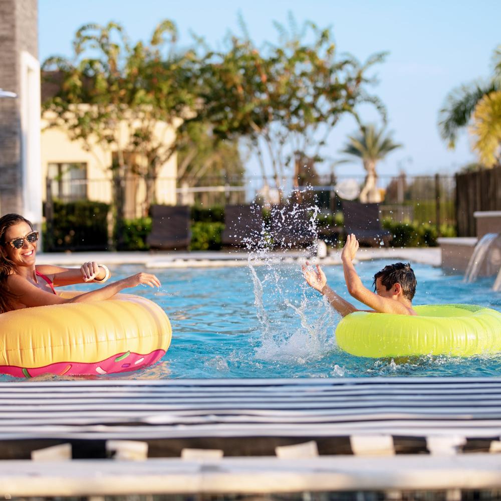 Mother and Son Each in Their Own Pool Tube Floaty, Splashing and Playing in the Pool, Enjoying the Beautiful Kissimmee Weather