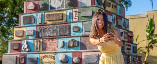 Girl in yellow dress takes photo in front of Monument of States in Downtown Kissimmee.