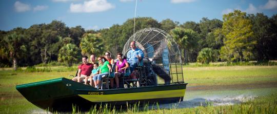 Group of people on a Wild Florida airboat turning through a marsh