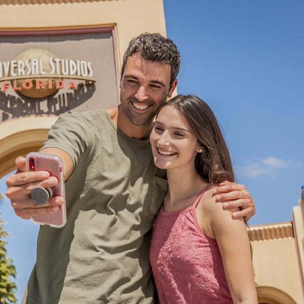 A man and a woman taking a selfie in front of the Universal Studios entrance.