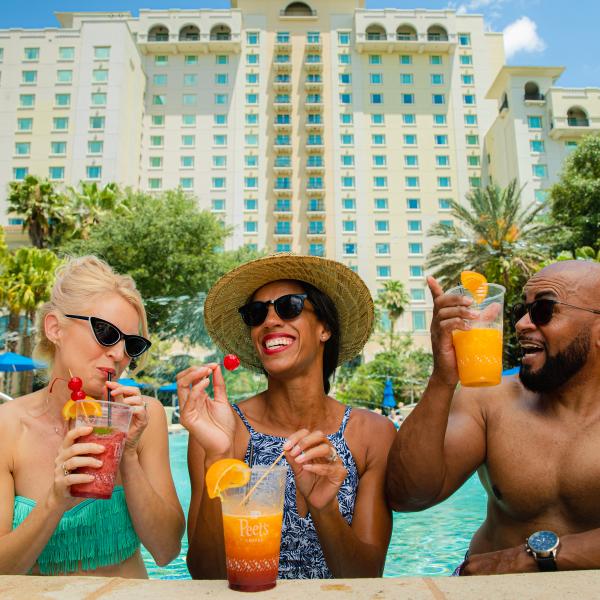 3 Friends poolside drinking tropical drinks at the Omni Orlando Resort at ChampionsGate