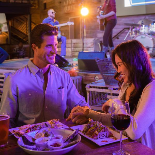 Couple eating dinner and laughing while live music is played behind them