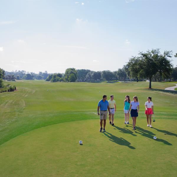 group of 5 friends walking to their next hole on the golf course on a summer day