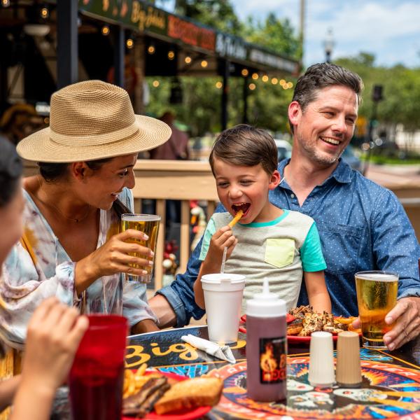 family dining outdoors with son excited to eat french fries