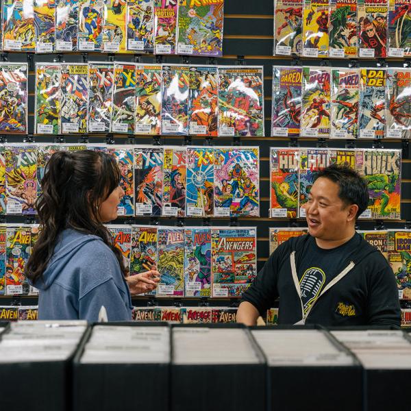 Ming Chen and Jen Bonner stand in front of a wall of colorful comic books