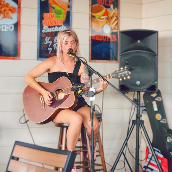 Musician performing live acoustic guitar and vocals at Crabby Bill’s in St. Cloud, Florida, with colorful seafood-themed posters in the background.