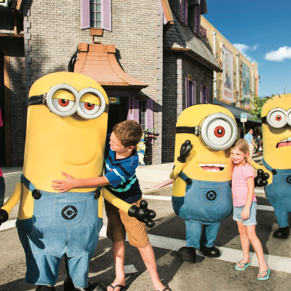 Children hug and interact with three Minion characters at Universal Orlando Resort. 