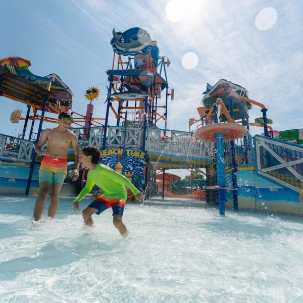 Three kids splash and play in the shallow pool at Island H2O Water Park’s colorful splash zone on a sunny day in Kissimmee, Florida.