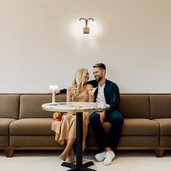 A couple enjoys drinks and conversation at a stylish café inside the ette hotel in Kissimmee, Florida, seated together on a modern tan sofa under soft ambient lighting.