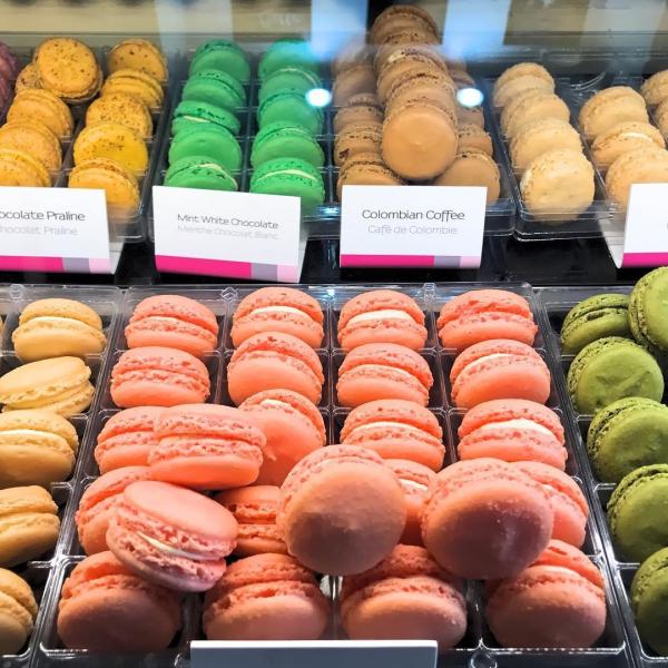Close-up of colorful macarons displayed in neat rows at Le Macaron in Kissimmee, featuring flavors like mint white chocolate, Colombian coffee, and chocolate praline.