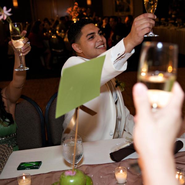 A bride and groom raise a joyous toast as they celebrate their wedding during dinner.