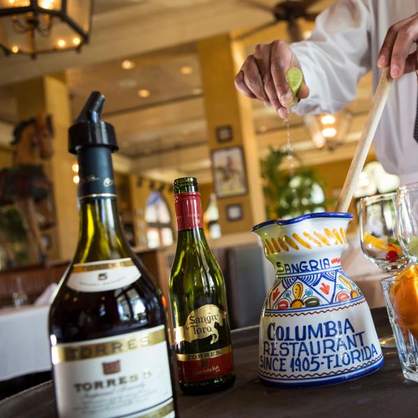 A man squeezing lime into a jar to prepare Sangria