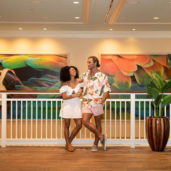 A couple poses in front of two large pieces of artwork in a resort.