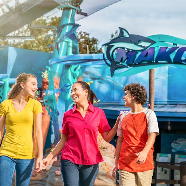 A women and two children walk in front of a rollercoaster at Sea World