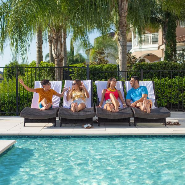 Family of four each sitting on a lounge chair by the pool