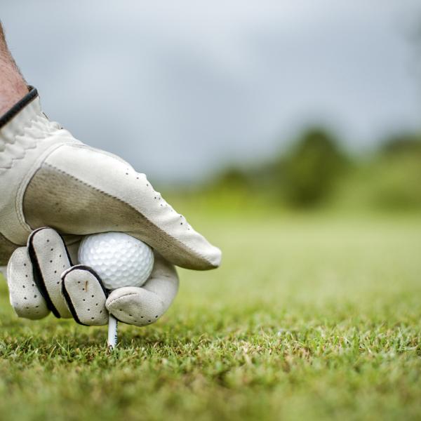 A man sets a golf ball on the tee 