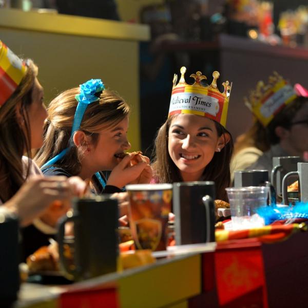 Guests wearing crowns enjoy dinner and live entertainment at Medieval Times Dinner & Tournament in Kissimmee, Florida, where medieval knights and royal festivities create an unforgettable dining experience.