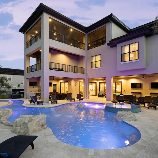Luxury vacation home in Kissimmee, Florida, with a glowing private pool, spacious lounge area, and multiple balconies perfect for relaxing evenings.