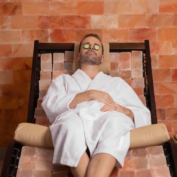 A man in a robe with cucumbers over his eyes at Relâche Spa at Gaylord Palms Resort & Convention Center 