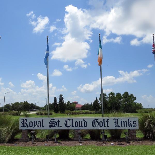 A sign that says Royal St. Cloud Golf Links with flags and a fairway in the background