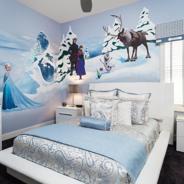 A Frozen-themed bedroom in a Kissimmee vacation home featuring character wall art of Elsa, Anna, Olaf, and Sven, with blue and white bedding and modern furnishings.