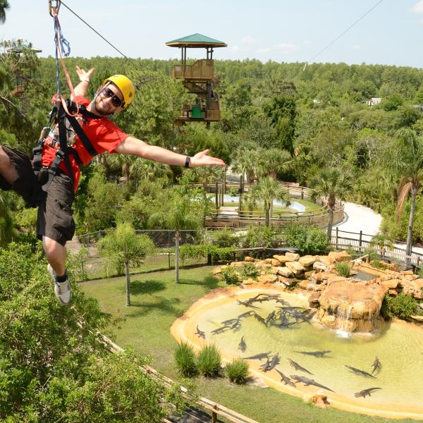 guy in red shirt on a zip line over Gatorland 