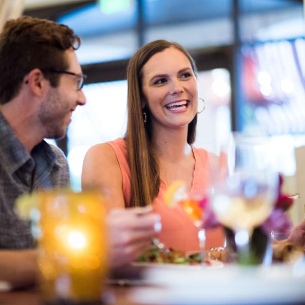 A woman laughs as her companion looks on during a delicious meal at an upscale restaurant.