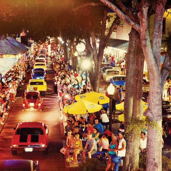 Crowds gather along Main Street in Old Town Entertainment District in Kissimmee, Florida, to watch a classic car cruise featuring vintage vehicles at night.