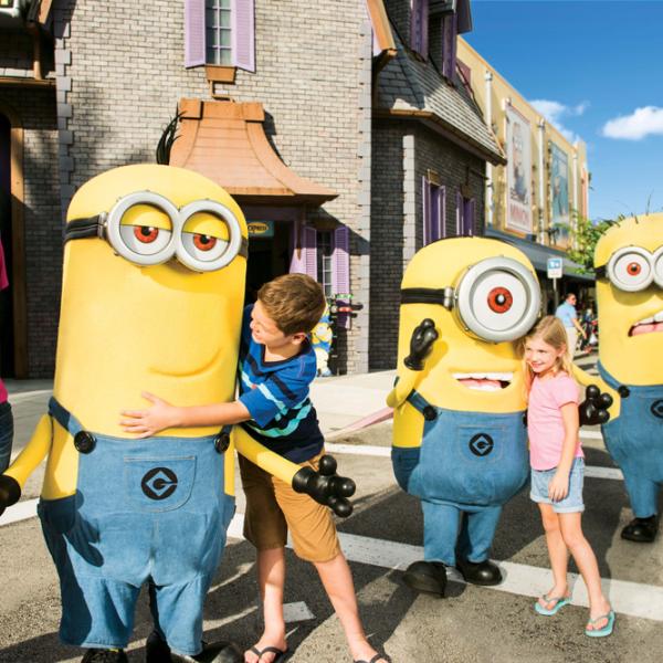 Children and their mom meet and pose with Minion characters at Universal Orlando Resort, smiling and enjoying a sunny day in the theme park’s colorful streets.