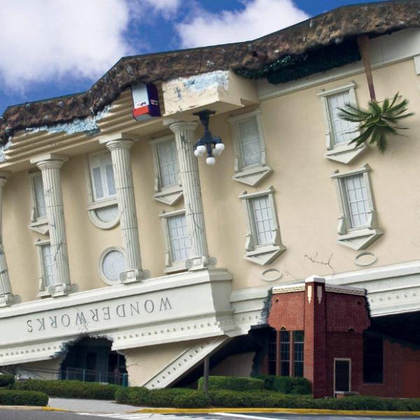 Exterior view of WonderWorks Orlando, designed to look like an upside-down classical building with cracked walls and palm trees jutting from the roof.