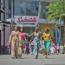 Four women enjoy a sunny day of shopping and strolling through Disney Springs, carrying colorful bags near Splitsville Luxury Lanes.