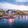 Evening view of Universal CityWalk in Orlando, Florida, with colorful lights reflecting on the water and a boat cruising along the canal near restaurants and entertainment venues.